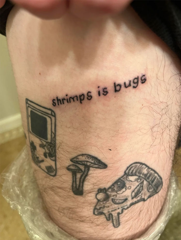 A tattoo featuring the phrase "shrimps is bugs" in small, bold, and minimalistic text across a person's leg. Surrounding this tattoo are other simple line tattoos, including a Game Boy, a mushroom, and a slice of pizza wearing sunglasses. The tattoos appear playful and quirky, contributing to the humorous tone of the "shrimps is bugs" phrase.