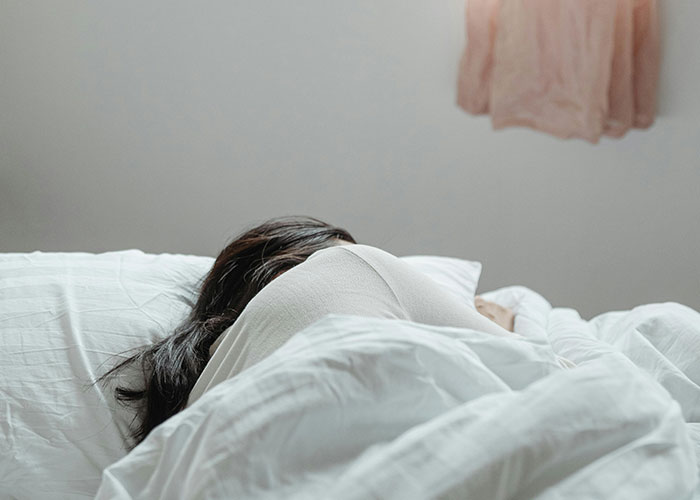 Person lying in bed facing away, illustrating common adult problems people wish someone warned them about earlier in life.