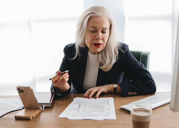 Mature woman reviewing documents at desk, highlighting common adult problems people wish they knew earlier in life.
