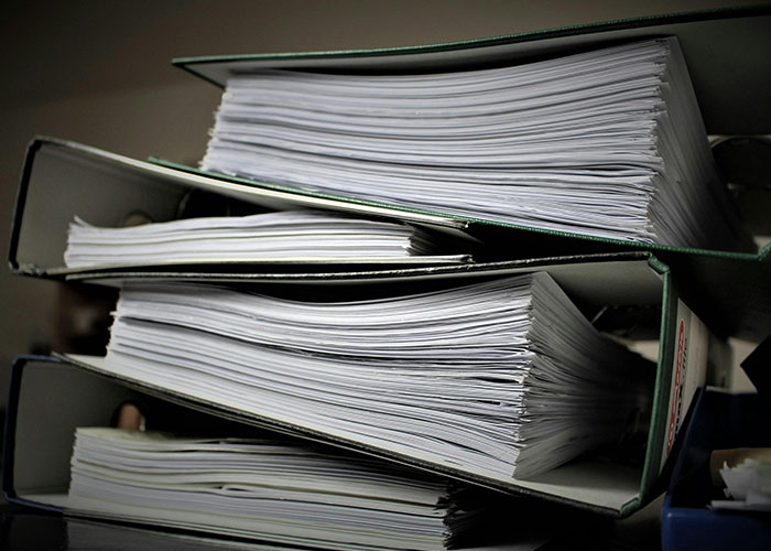 Thick binders filled with paperwork representing adult problems people wish someone warned them about earlier in life.