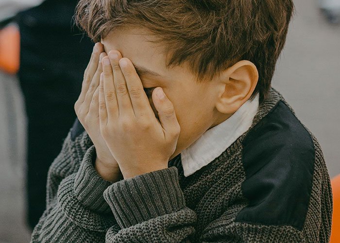 Young adult covering face with hands, illustrating common adult problems many wish they were warned about earlier.