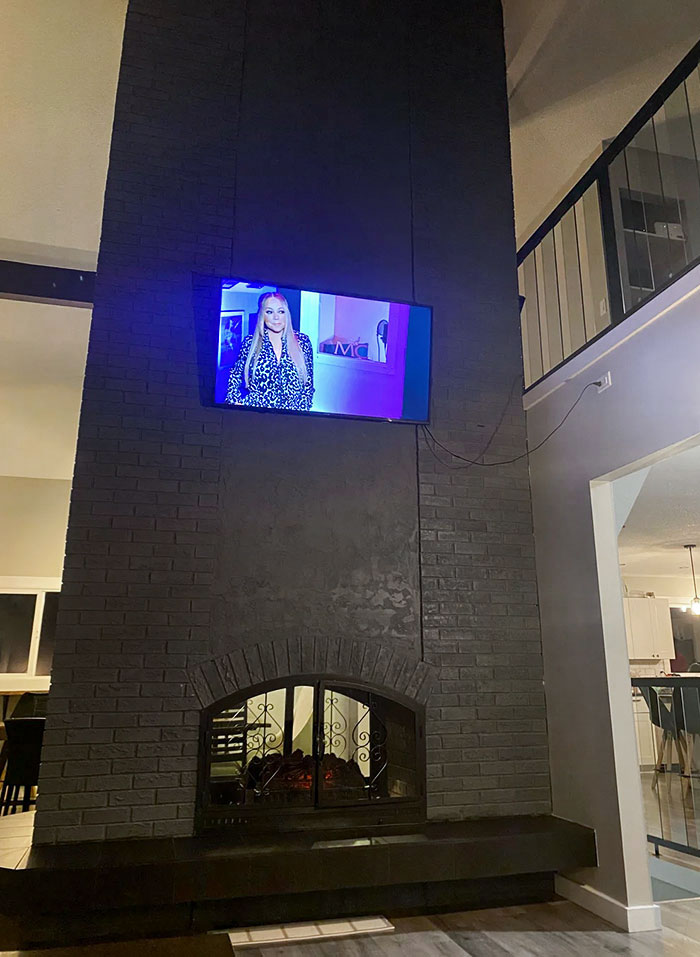 Airbnb House. TV Is Hung Halfway Up A Two-Story High Fireplace, Nearly Level With The Upper Floor