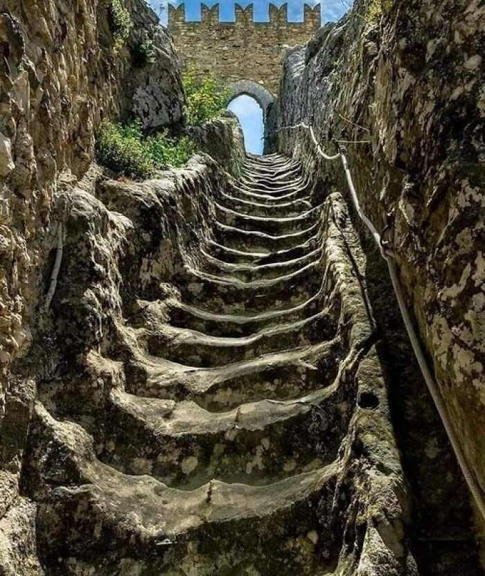 Ancient marvels: stone staircase carved into rocky terrain, leading up to a medieval stone archway.