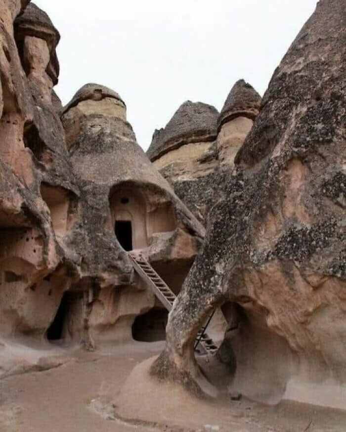 Ancient marvels: Rock formations with carved dwellings and wooden ladders, showcasing incredible historic architecture.