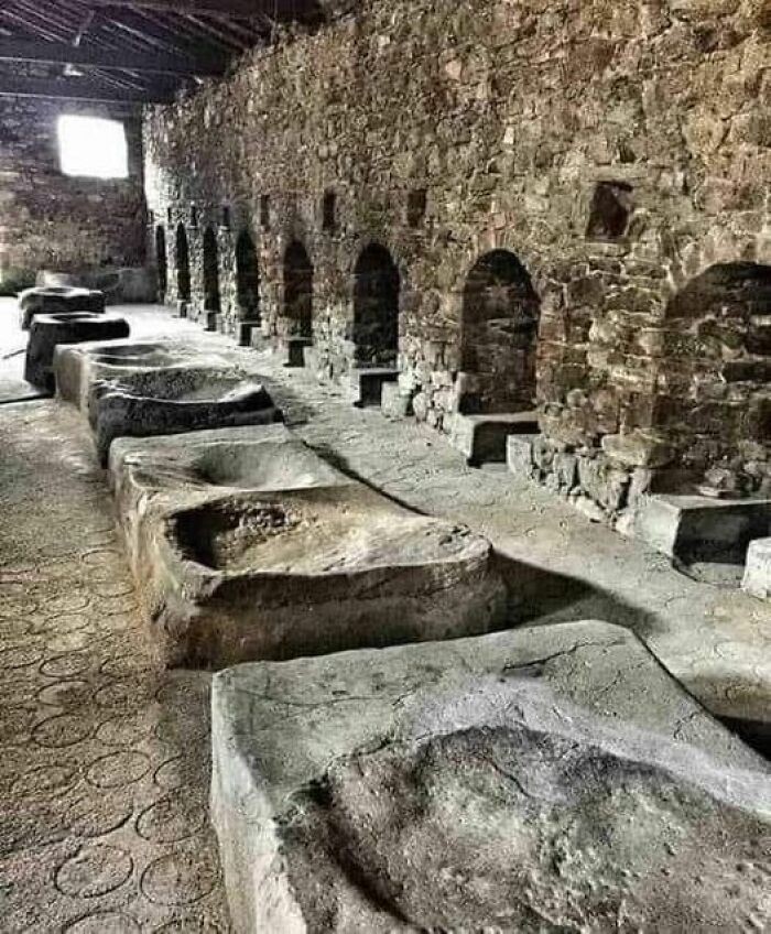 A row of ancient stone structures inside a stone-walled room, showcasing ancient marvels of architecture.
