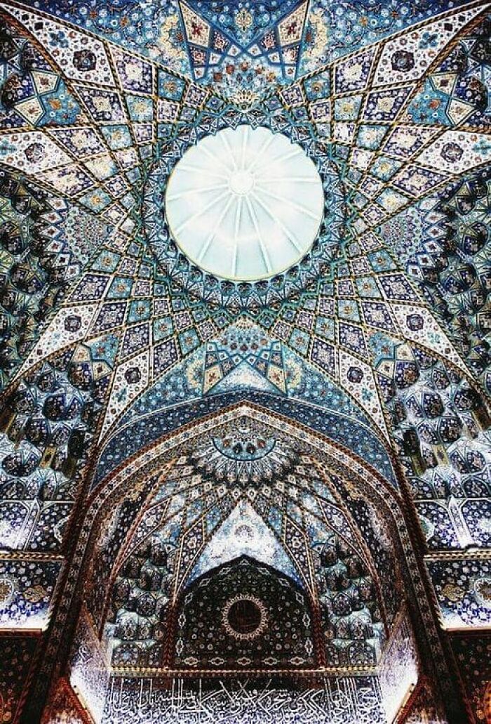 Intricate ancient marvel ceiling with ornate patterns and a central dome, showcasing stunning craftsmanship.