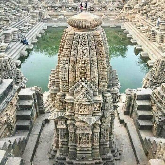 Ancient marvels: intricately carved stone temple with steps leading to a water reservoir.