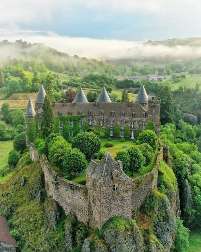 Ancient marvels: A stunning medieval castle surrounded by lush greenery and misty hills, showcasing timeless architecture.
