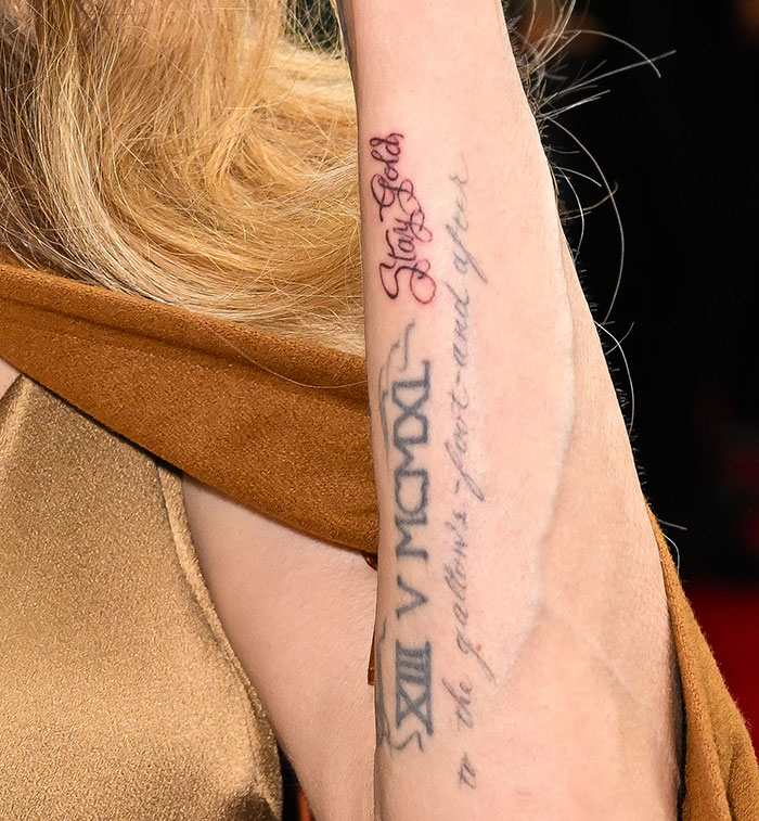 Forearm with tattoos featuring red and black text, related to Angelina Jolie and matching tattoo discussion. Forearm with tattoos featuring red and black text, related to Angelina Jolie and matching tattoo discussion.