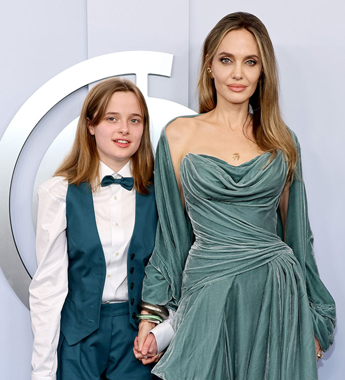 Angelina Jolie in a green dress and her child in a teal suit at a formal event. Angelina Jolie in a green dress and her child in a teal suit at a formal event.