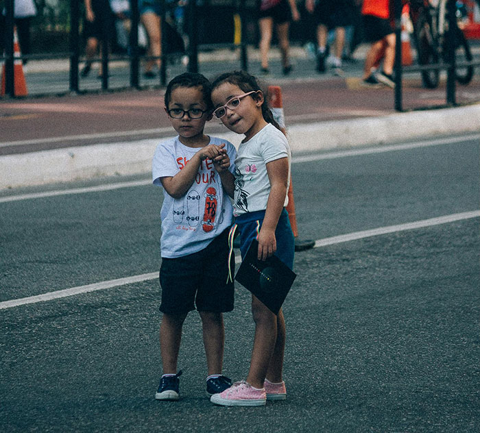 Two young children wearing glasses stand close together on a street, illustrating concerns about worst parents and child safety.