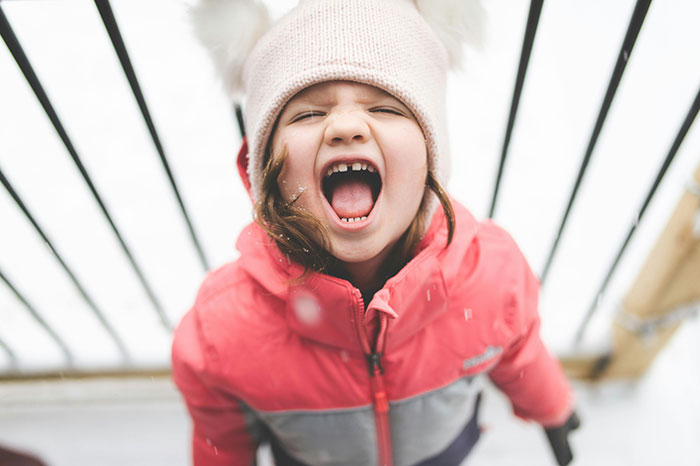 Young girl in a winter coat and hat playing outside, illustrating moments related to worst parents and child custody issues.