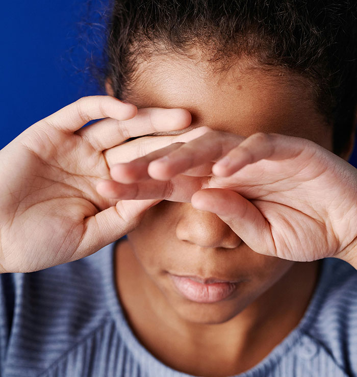 Close-up of a child covering their eyes, representing distress linked to encounters with the worlds worst parents and CPS cases.
