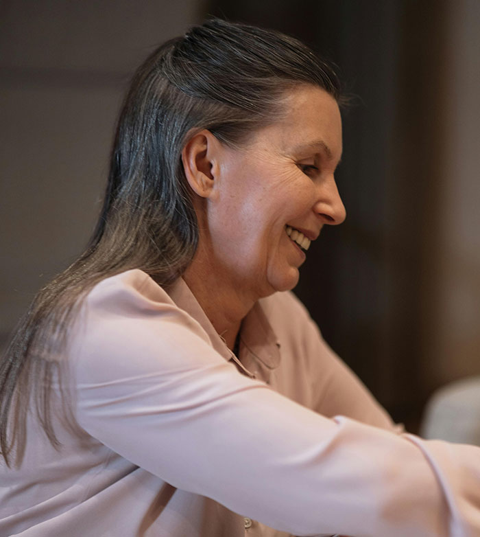 Middle-aged woman smiling warmly indoors, illustrating a moment related to worst parents and child protective services.