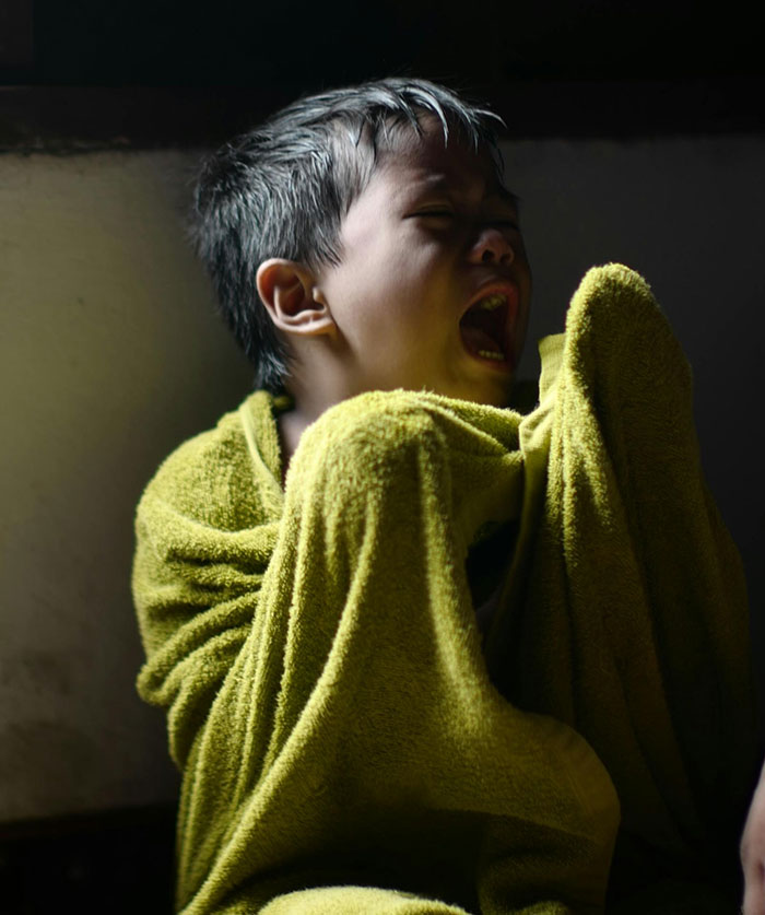 A young child wrapped in a yellow towel crying, illustrating distress related to encounters with the world’s worst parents.
