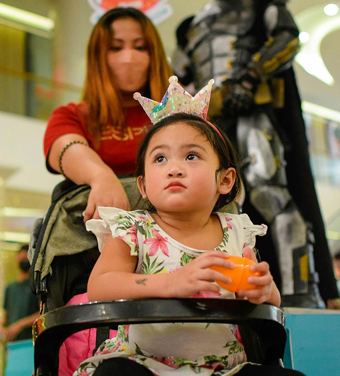 Young girl wearing a crown in a stroller with an adult behind her, highlighting issues related to worst parents and CPS intervention.