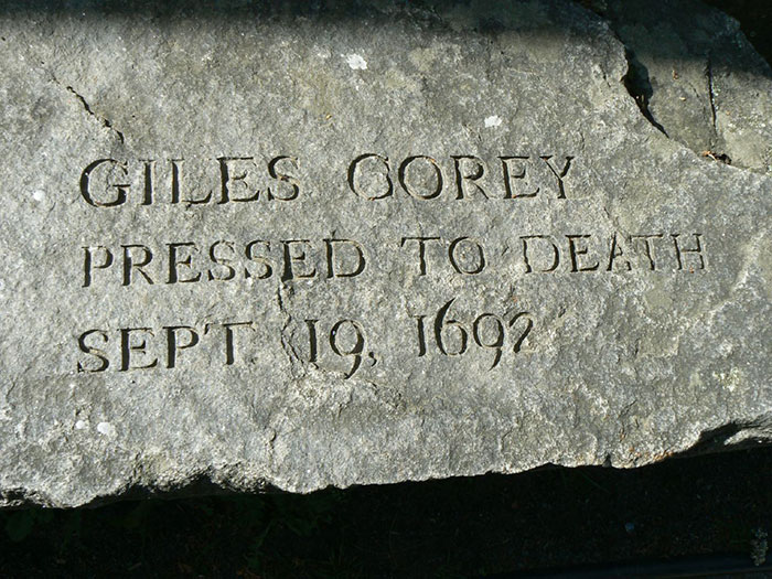 Engraved stone for Giles Corey, pressed to death in 1692, representing iconic last words shared in history.