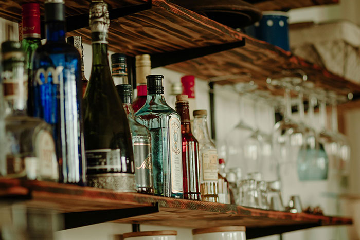 Various bottles and hanging glasses on wooden shelves in a cozy bar setting, illustrating iconic last words atmosphere.