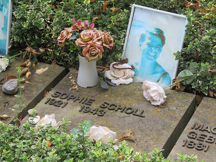 Gravestone of Sophie Scholl surrounded by flowers and greenery, symbolizing iconic last words in history.