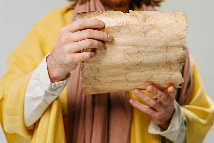 Person dressed in historical clothing holding a weathered, ancient parchment with iconic last words in history concept.