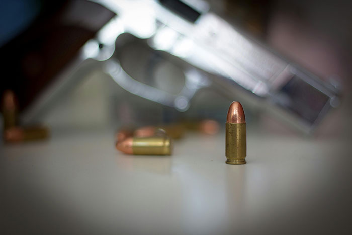 Close-up of handgun and bullets on surface, illustrating iconic last words shared by 45 people in history.