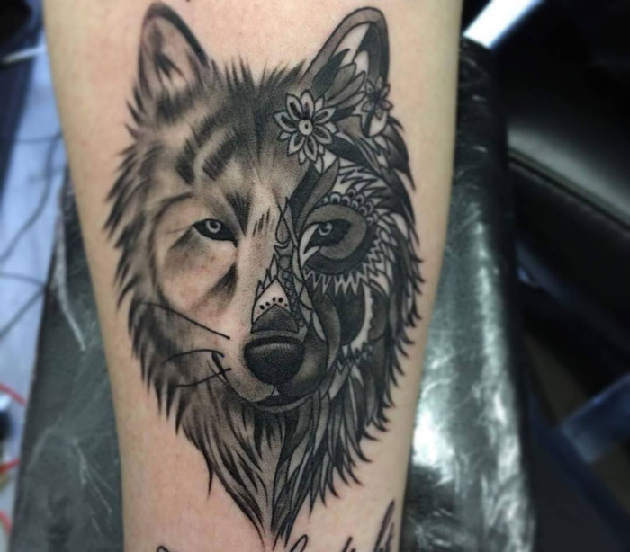 Wolf and intricate design sleeve tattoo on a person's arm.