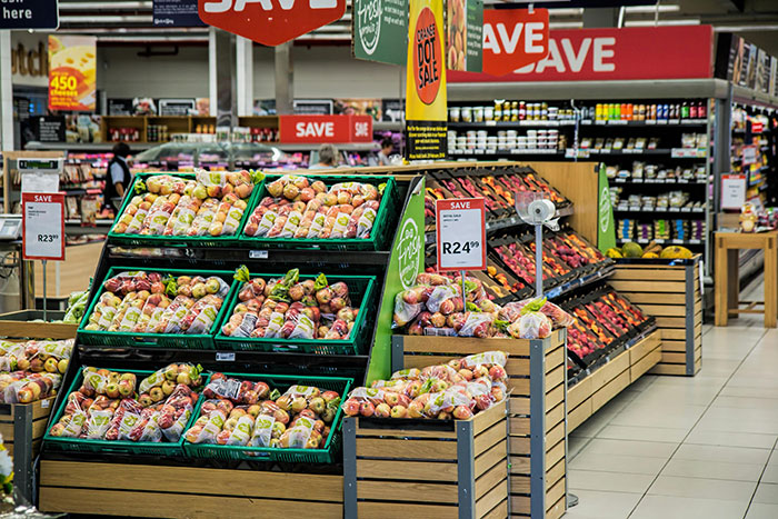 Grocery store fresh produce display with apples and price signs highlighting savings on fruit.