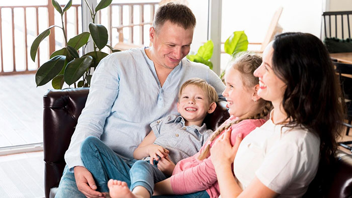 A happy family sitting together on a couch, parents with two children, smiling and enjoying each other's company. A happy family sitting together on a couch, parents with two children, smiling and enjoying each other's company.