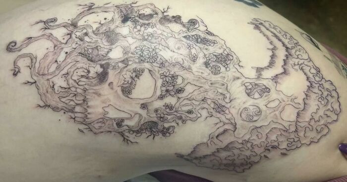 Intricate tattoo design of a skull and floral patterns shared in a Facebook group about unusual tattoos.