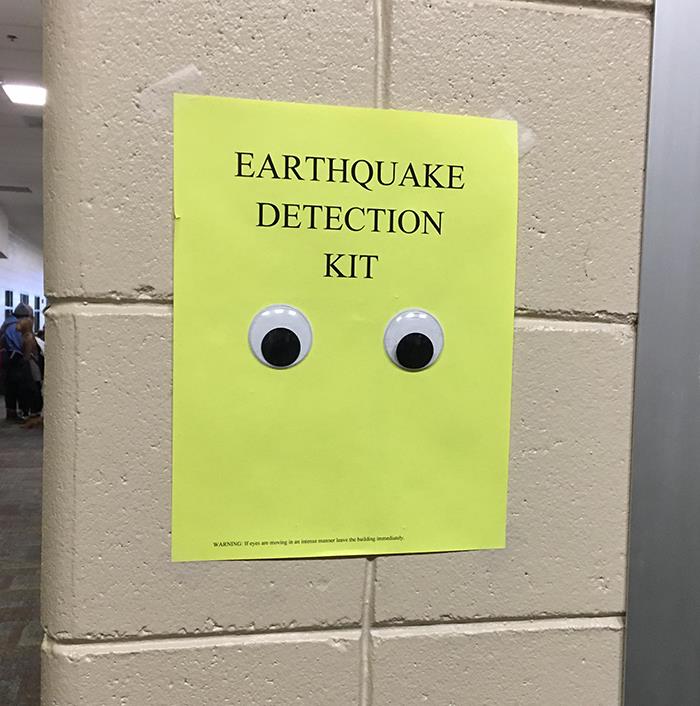 Funny earthquake detection kit sign with googly eyes on yellow paper posted on beige wall, a science meme.