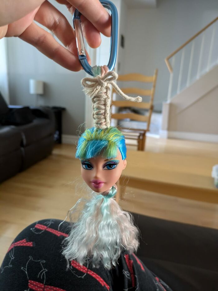 Soy voluntaria en una tienda de segunda mano y me quedé con esta cabeza de muñeca y algunos cordones de una bolsa de regalo estropeada e hice esta abominación. Mi madre lo odia.