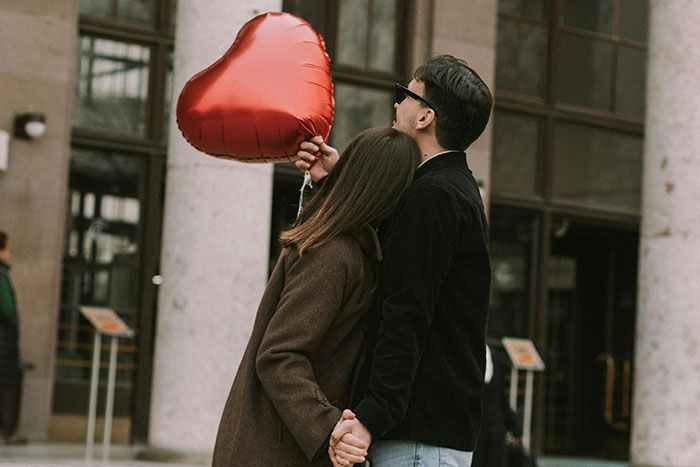A couple holding a heart balloon, symbolizing silent signals of falling out of love.