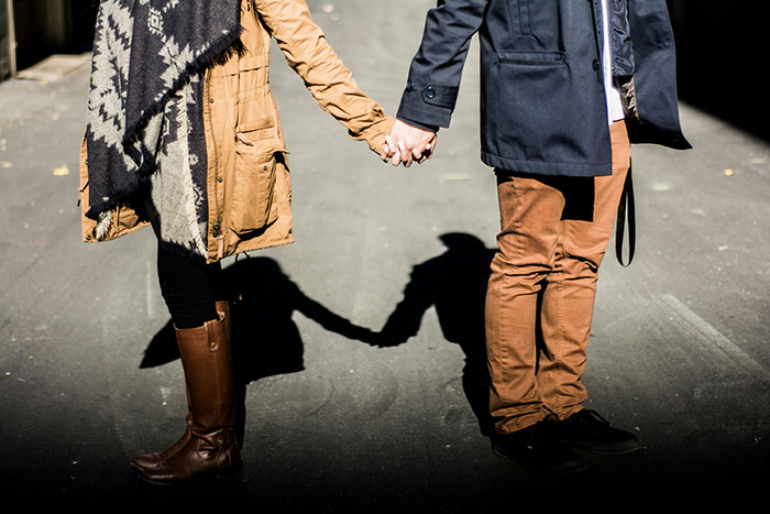 Couple holding hands on a street, capturing a moment potentially signifying falling out of love.