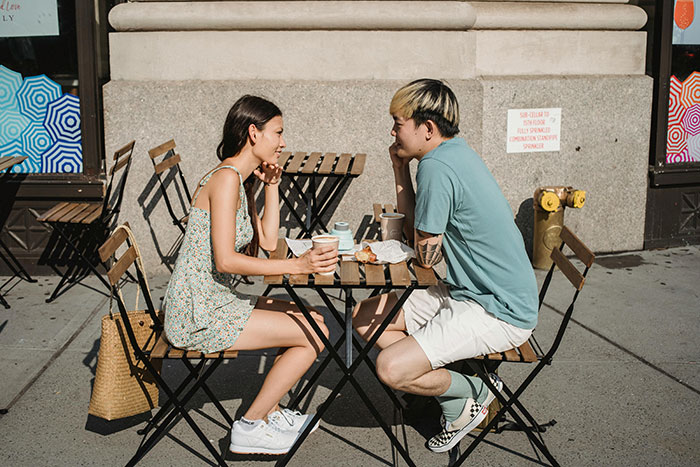 Couple at an outdoor cafe looking distant, silent signals of falling out of love.