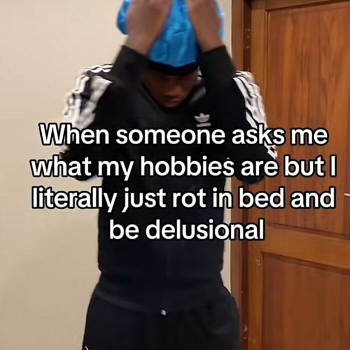 Person in tracksuit with a humorous meme text about life's ups and downs, adjusting a blue cap indoors.
