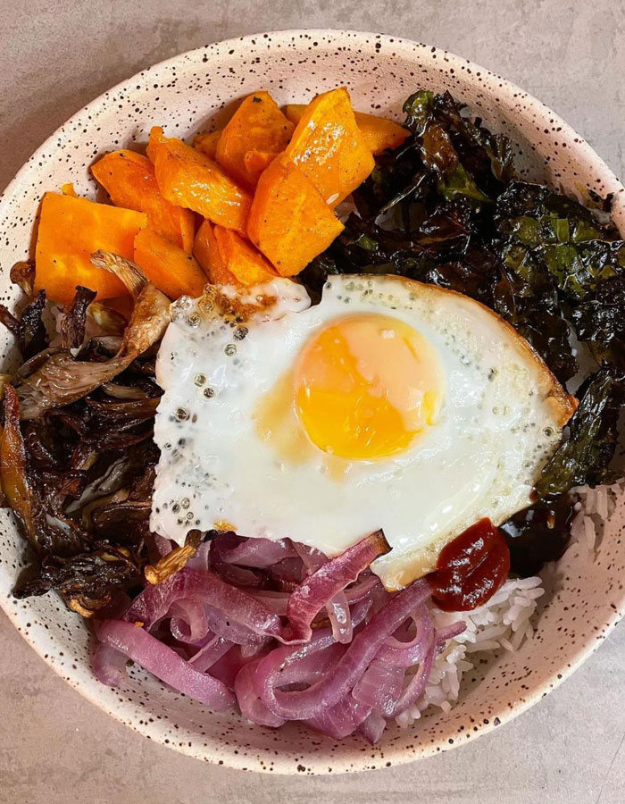 A vibrant lunch idea featuring a bowl of rice topped with a sunny-side-up egg, sautéed mushrooms, roasted sweet potatoes, pickled red onions, and a side of leafy greens. A vibrant lunch idea featuring a bowl of rice topped with a sunny-side-up egg, sautéed mushrooms, roasted sweet potatoes, pickled red onions, and a side of leafy greens.