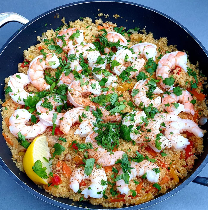 A healthy lunch idea featuring a pan of cooked quinoa topped with seasoned shrimp, garnished with fresh parsley and served with a lemon wedge. A healthy lunch idea featuring a pan of cooked quinoa topped with seasoned shrimp, garnished with fresh parsley and served with a lemon wedge.
