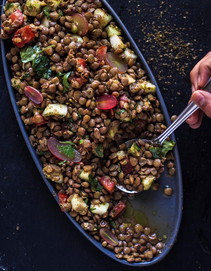 A lunch idea featuring a vibrant lentil salad with grapes, diced veggies, and herbs on an oval plate, ready to be served with a spoon. A lunch idea featuring a vibrant lentil salad with grapes, diced veggies, and herbs on an oval plate, ready to be served with a spoon.