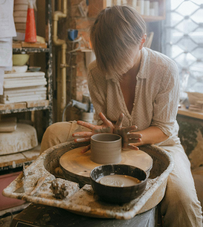 Woman focused on pottery wheel crafting clay, showcasing subtle attractive traits often unnoticed by women.