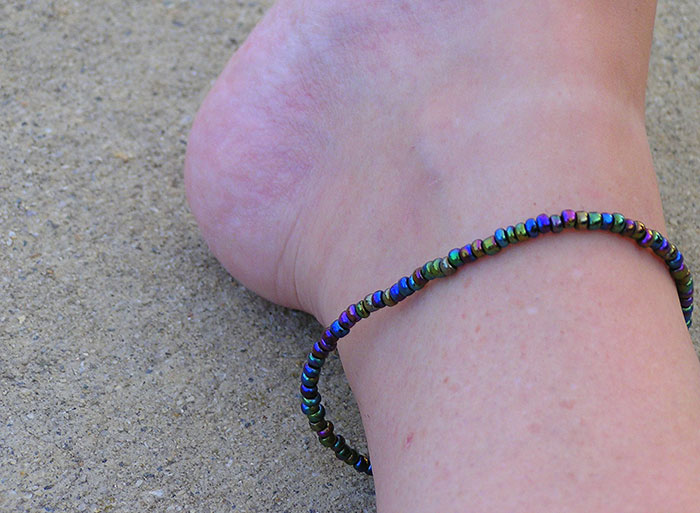 Close-up of a woman's ankle wearing a colorful beaded anklet, highlighting attractive minor details on women.