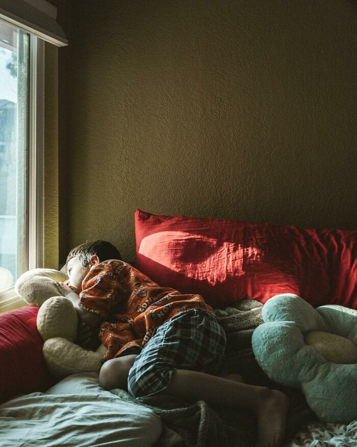Young child lying on a bed by a window, hugging a stuffed toy, illustrating the theme of white lies backfiring.