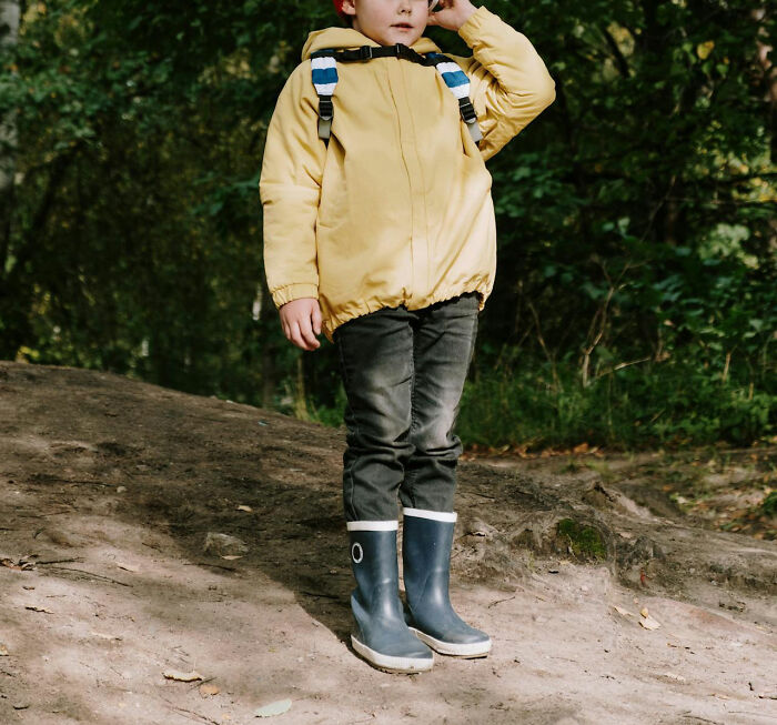 Child in a yellow jacket and rain boots standing outdoors, illustrating moments when white lies totally backfired on people.