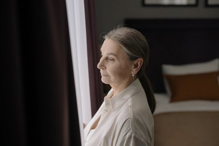 Woman in a white shirt looking thoughtfully out a window, conveying emotions women want men to finally understand.