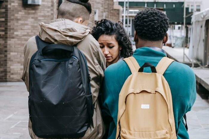 A woman expressing emotions while two men with backpacks sit close by, highlighting things women want men to understand.