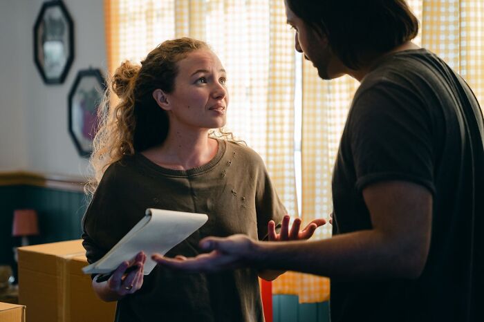 Woman holding notepad speaking passionately to man in a home setting, illustrating things women want men to understand