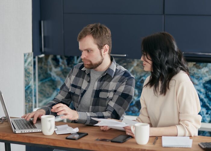 A man and woman discussing documents and laptop work, focusing on communication women want men to understand.