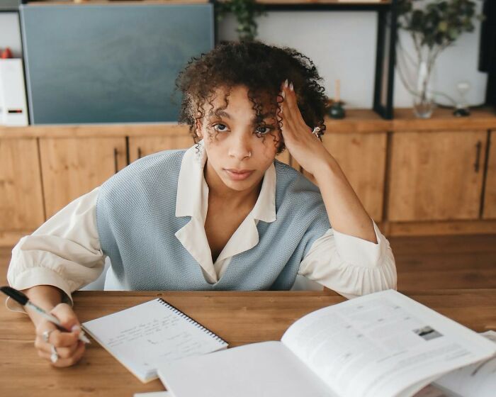 Young woman studying and writing notes at a wooden table, portraying emotions women want men to finally understand