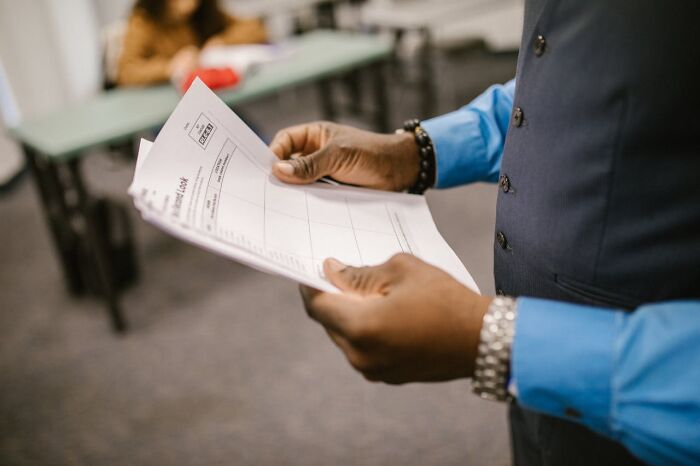 Person in blue shirt and vest holding documents, illustrating moments when white lies totally backfired on people.