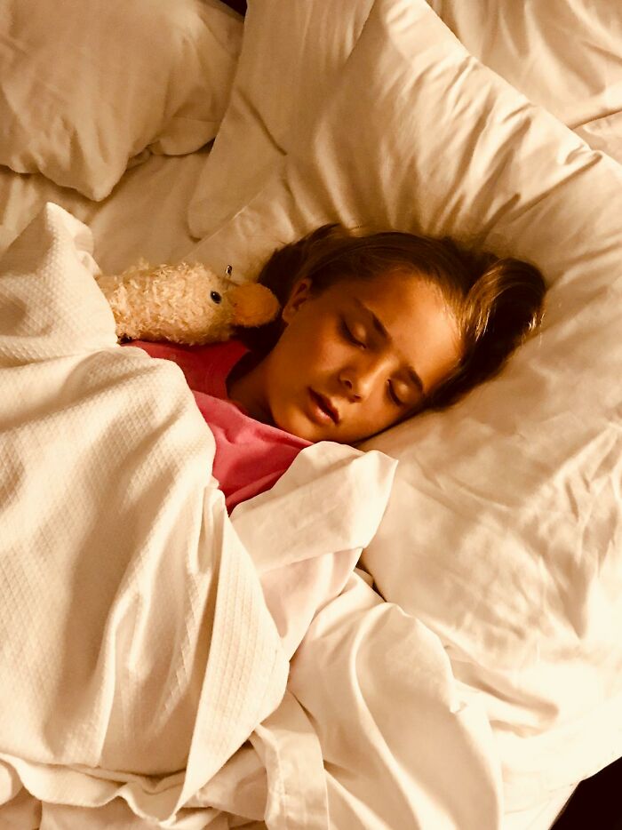 Young person sleeping peacefully in bed holding a stuffed animal, illustrating innocence before white lies backfired.
