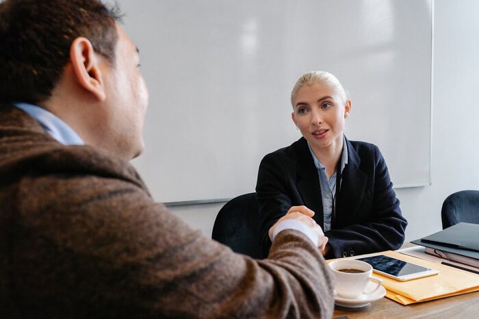A woman and man shaking hands in a meeting, illustrating communication and understanding between women and men.